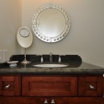 Bathroom cherry cabinets with green granite counter top and decorative mirror
