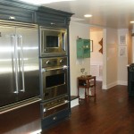 Blue kitchen cabinets with stainless steel appliances and hardwood floor
