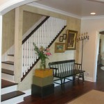 Interior Remodeled English Cottage entrance with brown and white stairway and wood bench