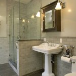 Mirror above Bathroom pedestal sink, shower with glass enclosure and stone tile work
