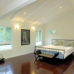 Bedroom with dark hardwood floors white decorative beams and decorative bed
