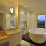 Modern bathroom with white cabinetry, white oval soaking tub and wall mirror