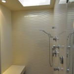 Modern enclosed shower with decorative wavy stone wall, stone bench and skylight